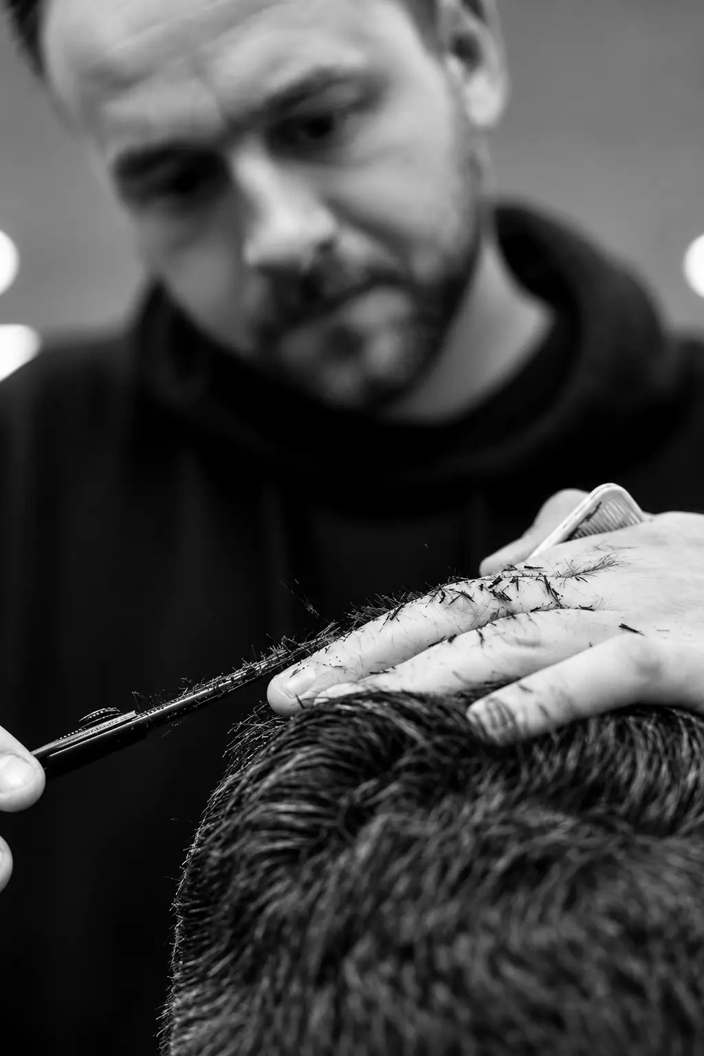 Detail strihu nožnicami, barber v pozadí