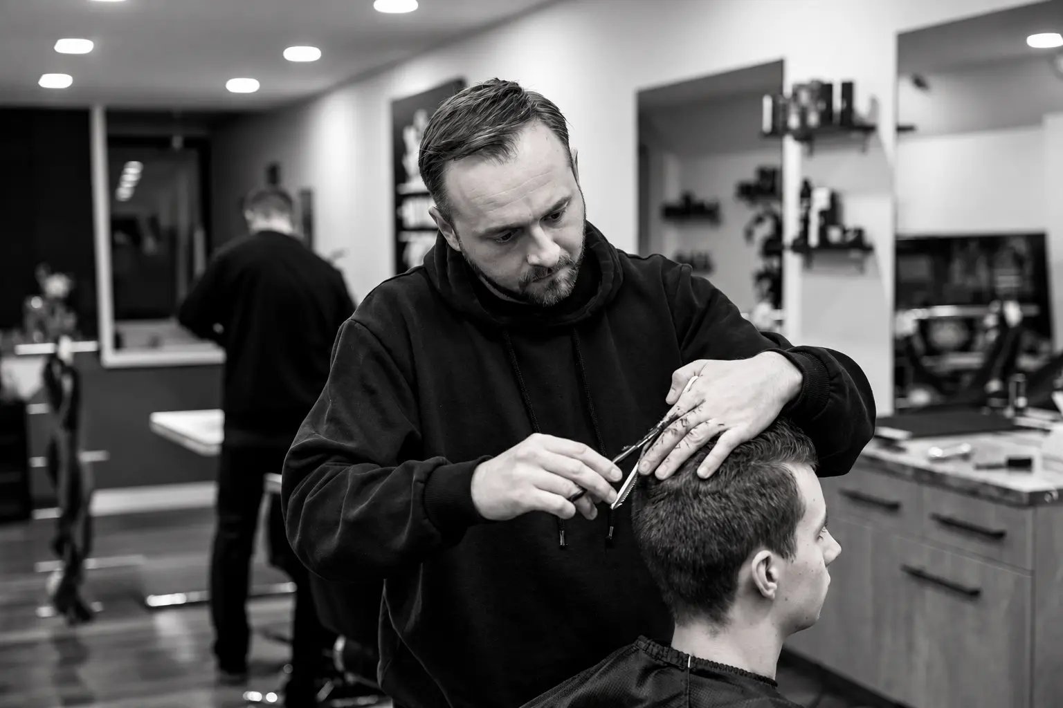 Barber v SEVAS strihá zákazníka nožnicami